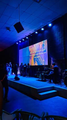 Palco iluminado com projeção em tela ampla e estrutura de luz azul